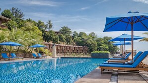 A pool area with blue umbrellas, lounge chairs, and a wooden deck.
