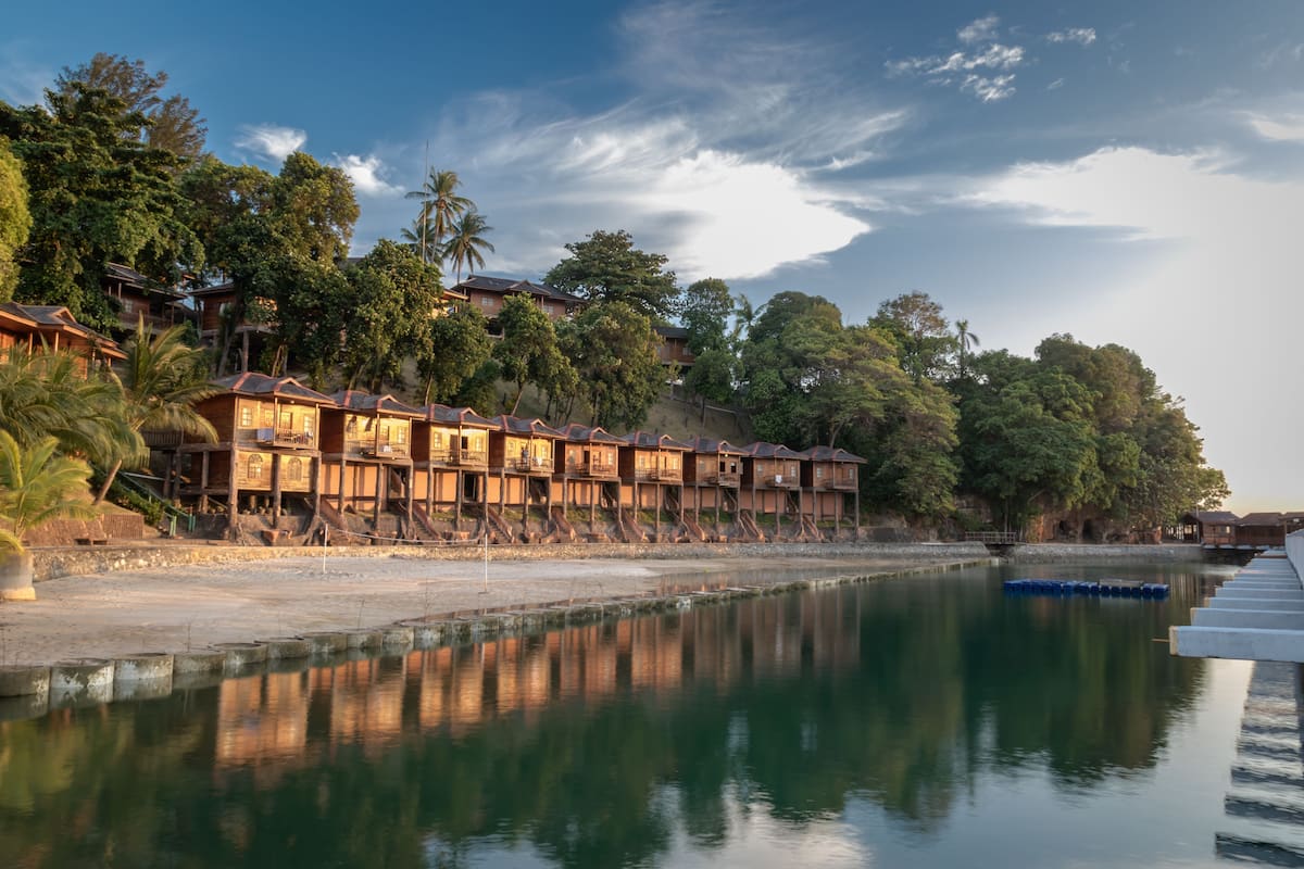 A waterfront hotel with multiple wooden buildings, a calm river, and lush greenery.