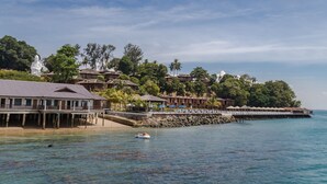 A coastal resort with overwater bungalows, a pier, and a statue.