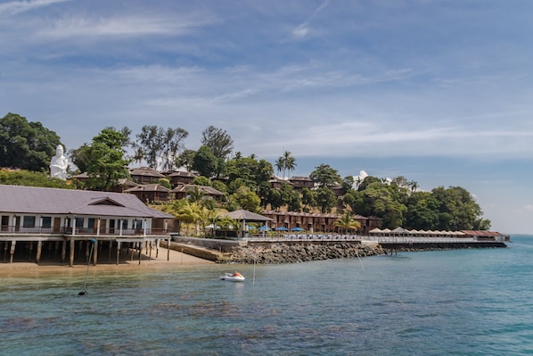 A coastal resort with overwater bungalows, a pier, and a statue.