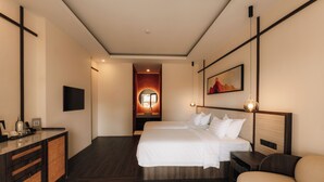A hotel room with two beds, a desk, a dresser, and a large mirror.