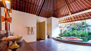 Un espace spa doté d’un sol carrelé, d’un plafond en bois, d’une grande fenêtre donnant sur un jardin et d’un vase décoratif posé sur une table en bois.