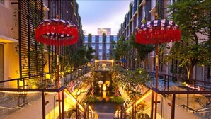 A modern hotel entrance with a central staircase, glass railings, and decorative red umbrellas. - Ananta Legian Hotel (Legian)
