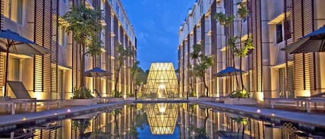 Un hôtel moderne doté d’un atrium central, d’un bassin d’eau aux reflets changeants et de façades aux lignes symétriques.