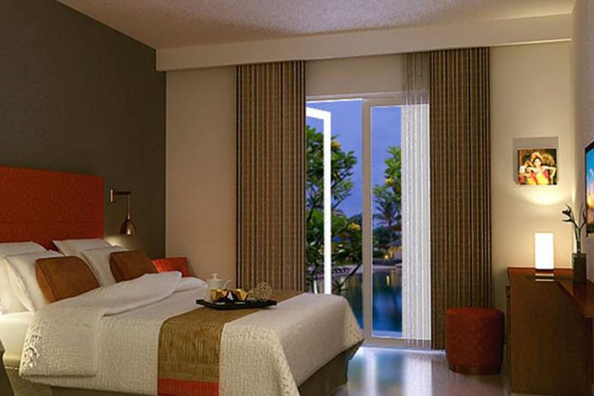Quarto de hotel com uma cama grande, uma escrivaninha, uma cadeira e vista para o exterior.