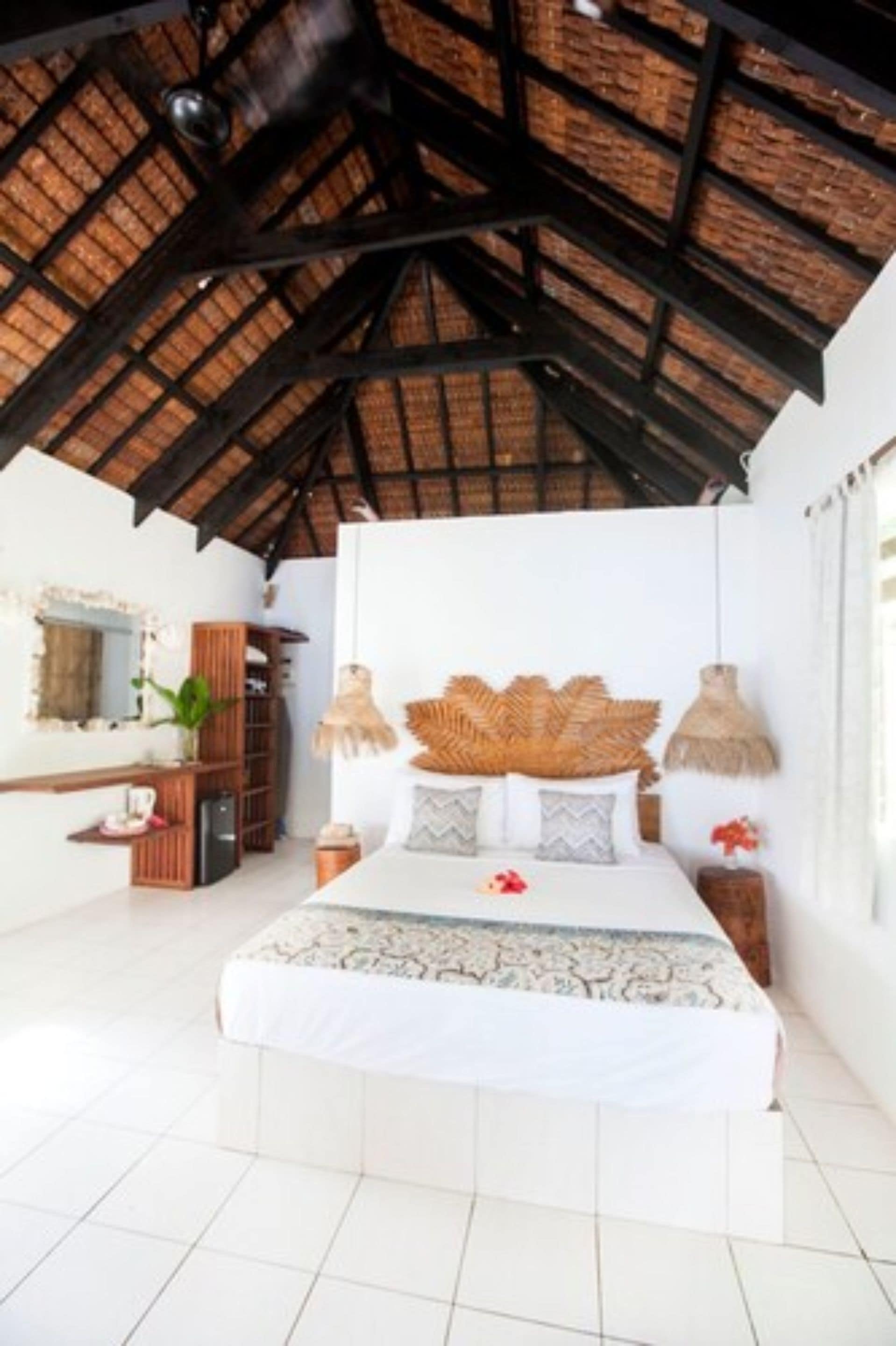 A bedroom with a bed, a nightstand, a mirror, a shelf, and a ceiling fan.