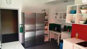 A compact kitchen with a stainless steel refrigerator, a microwave, and a dishwasher. There is a white countertop and a small trash bin. - Gaestehaus Kaiserpassage - Hostel (Karlsruhe)