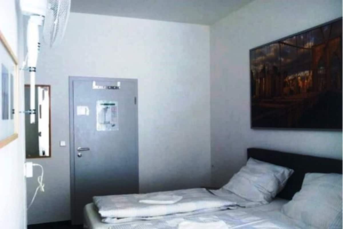A hotel room with a bed, a door with a water dispenser, and a painting on the wall.