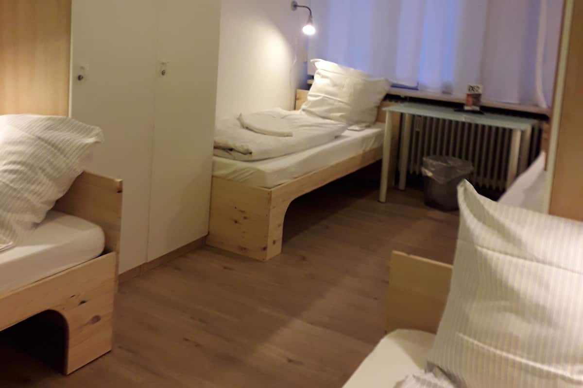 A small, compact room with a bed, a desk, and a wardrobe.