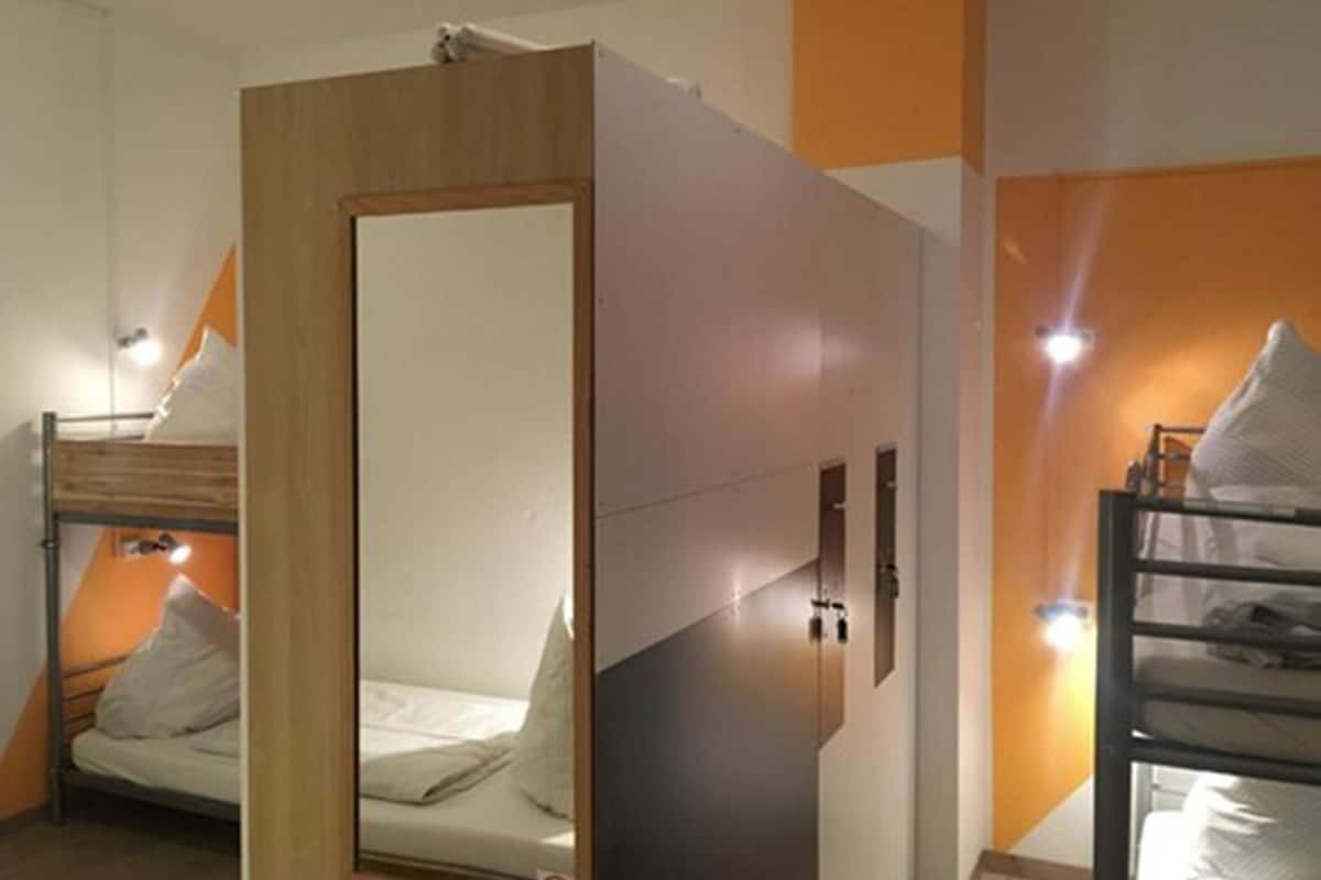 A room with bunk beds, a wooden-framed mirror, and a white wall with orange accents.