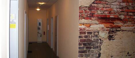 A hallway with a brick wall mural, doors, and a reception sign.