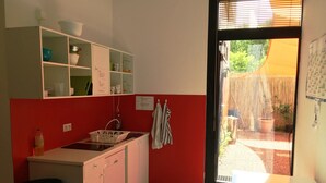 A kitchen with white cabinets, a sink, and a window overlooking a garden. - Gaestehaus Kaiserpassage - Hostel (Karlsruhe)