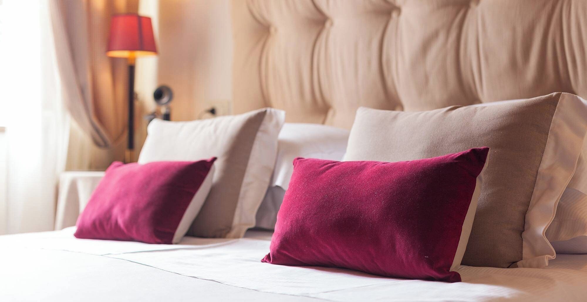 Una habitación de hotel con una cama grande, dos almohadas y una mesita de noche con lámpara.