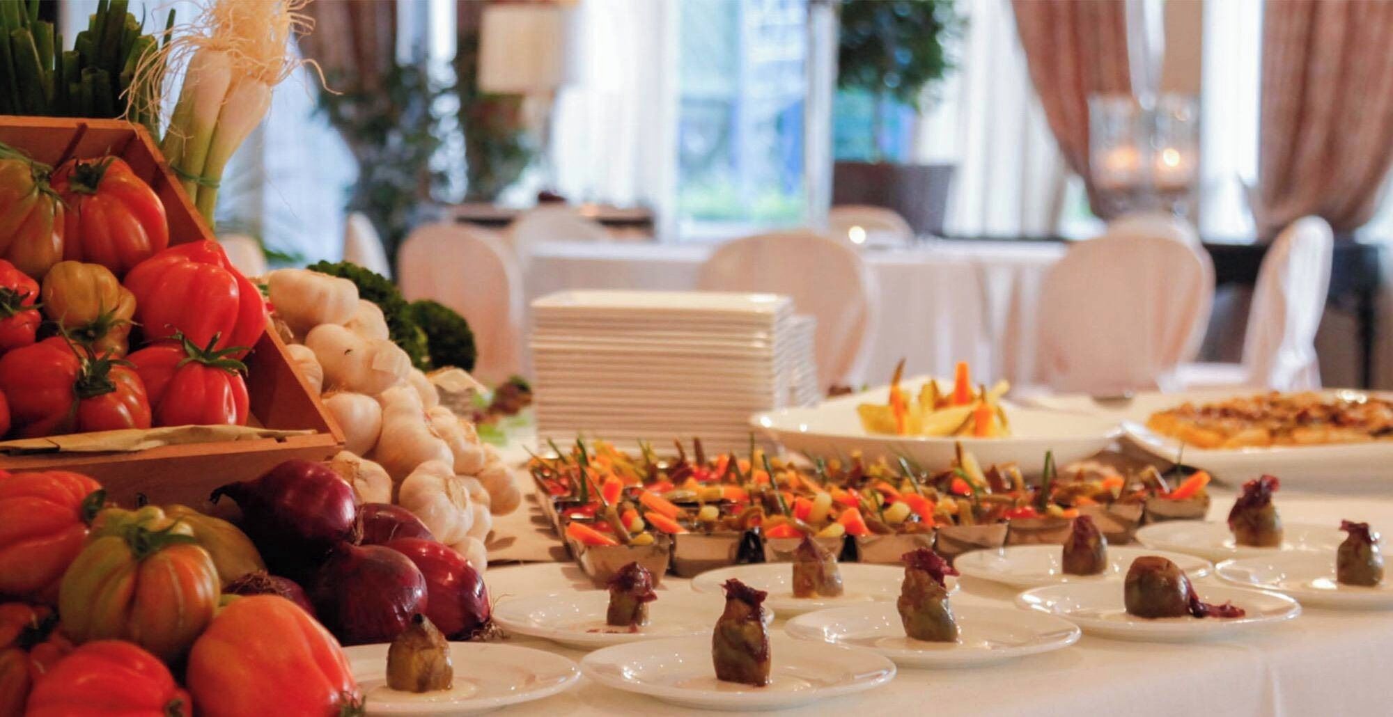 Una mesa de buffet con diversos alimentos, entre ellos verduras, frutas y aperitivos.