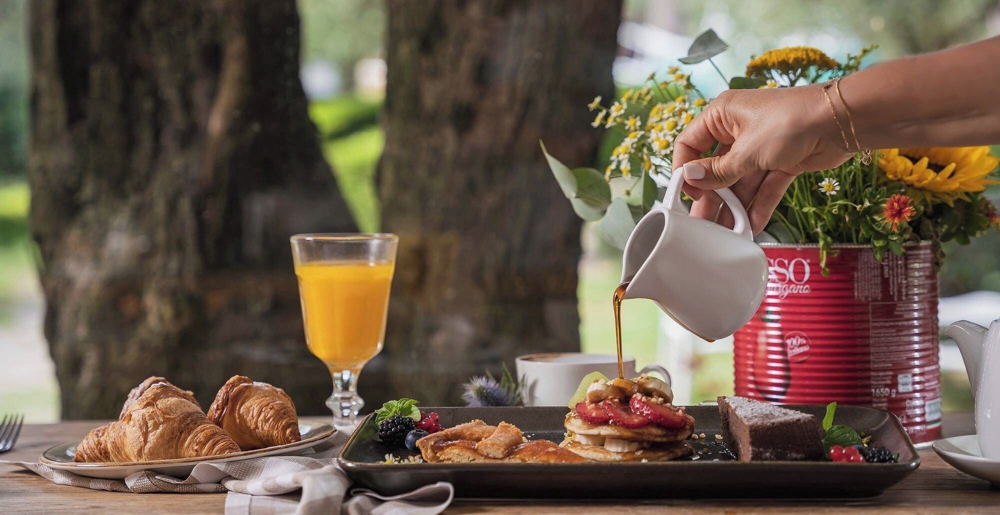 A breakfast setting with croissants, pancakes, and a drink being poured.