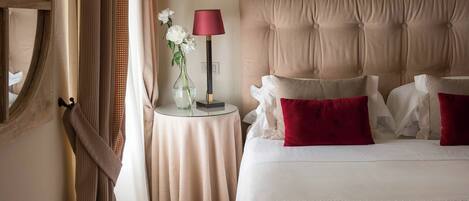 Una habitación de hotel con una cama grande, una mesita de noche con lámpara y un jarrón con flores.