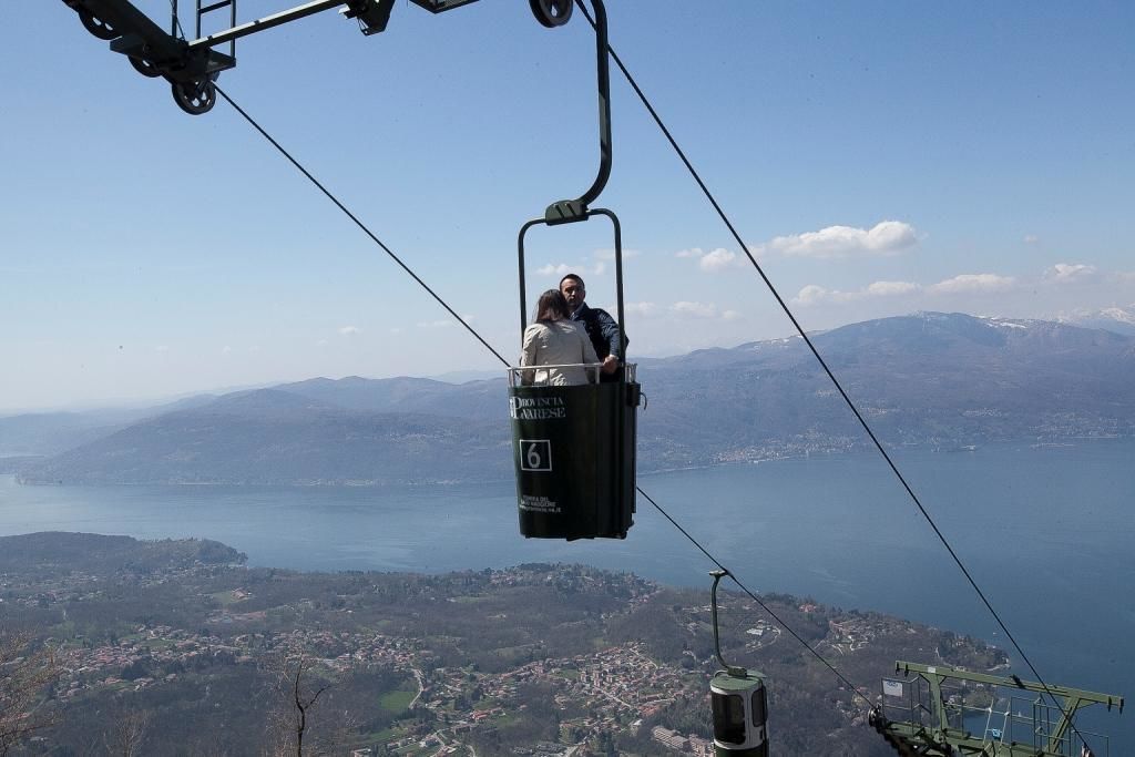 A cable car with two passengers, offering a view of a lake and distant mountains.