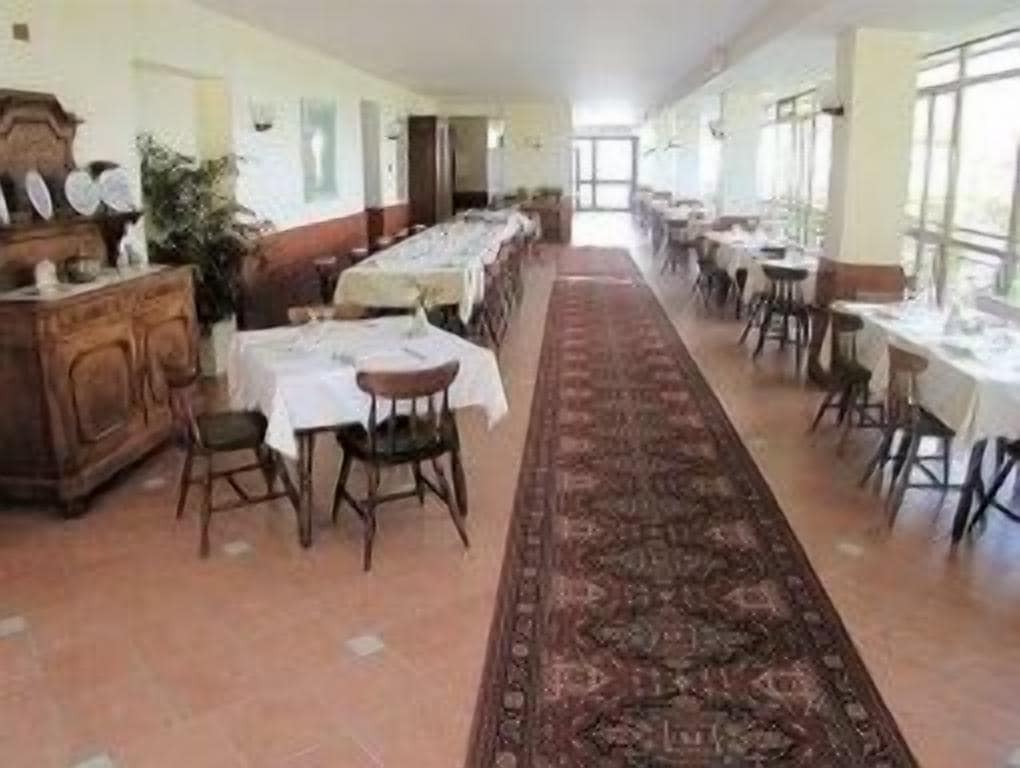 A long dining hall with multiple tables and chairs, a central aisle, and a patterned carpet.