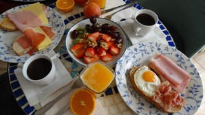 A breakfast table with plates of food, a bowl of fruit, and cups of coffee. - Hostal la Paloma II (Calpe)