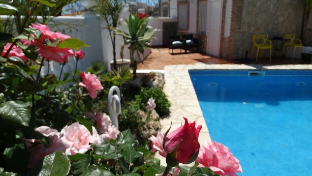 A pool area with a stone wall, a white chair, and a yellow chair. - Hostal la Paloma II (Calpe)