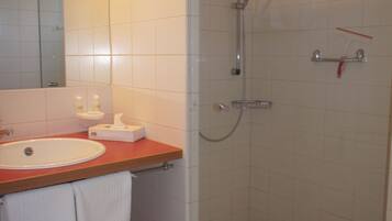 A bathroom with a sink, mirror, and shower.