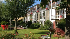 A hotel with a garden patio, outdoor seating, and a large red planter. - AngerResidenz (Zwiesel)