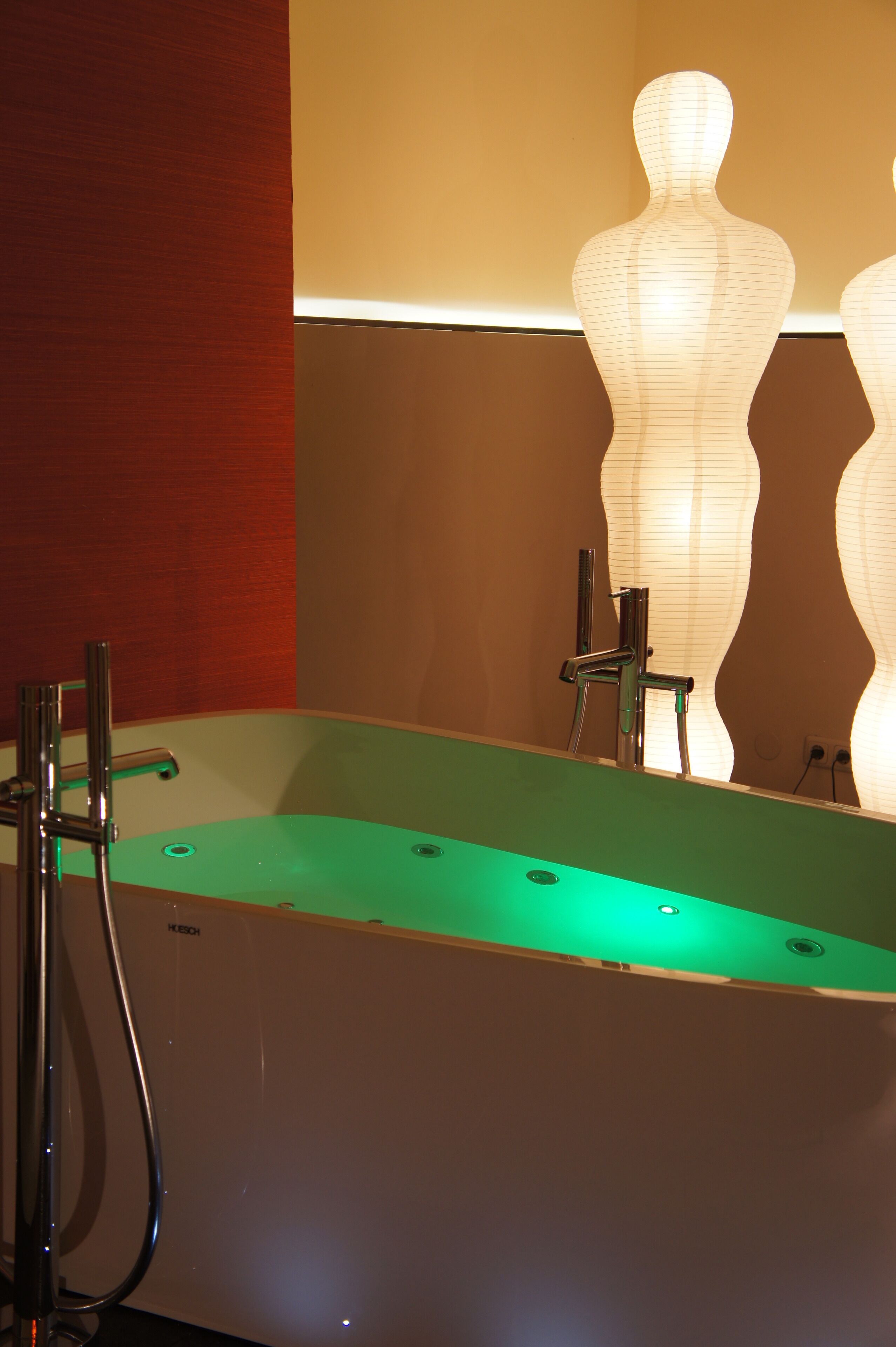 A bathroom with a green bathtub, a mirror, and a wall-mounted towel rack.