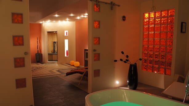 A modern bathroom with a large bathtub, a mirror, and a wall with a grid of square panels. - AngerResidenz (Zwiesel)