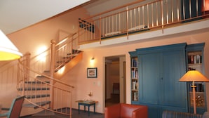 A multi-level living space with a staircase, a blue cabinet, and a red chair. - AngerResidenz (Zwiesel)