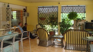 Un café con sillas de metal, una mesa y plantas en macetas.