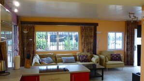 Una sala de estar con un conjunto de sofá, una mesa de centro y una zona de cocina con un armario rojo.