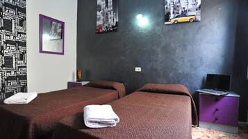 A hotel room with two beds, a desk with a laptop, and a wall with framed pictures.