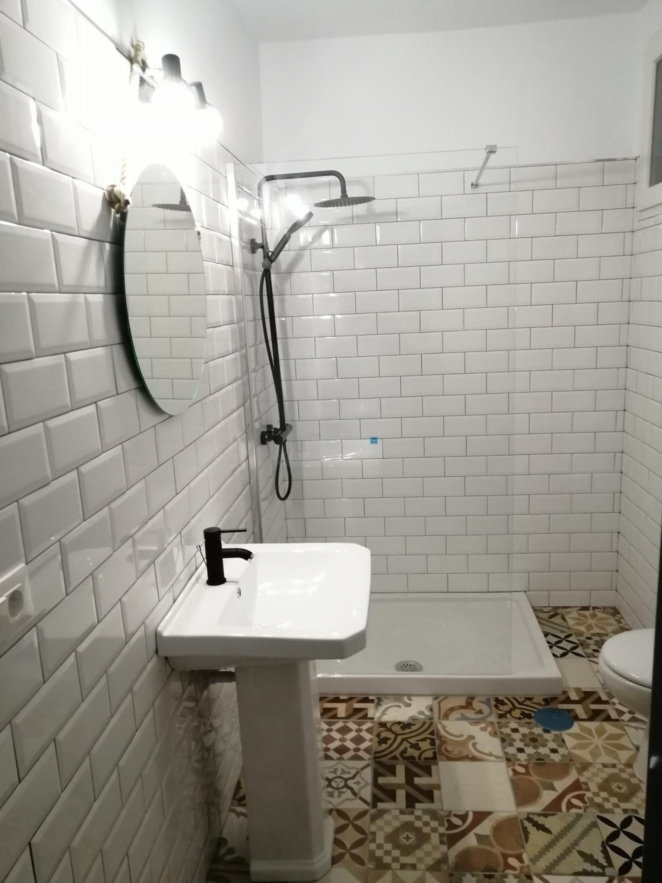 A bathroom with white tiled walls, a white sink, and a shower area.