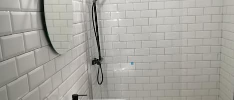 A bathroom with white tiled walls, a white sink, and a shower area.