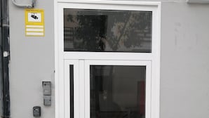 Una puerta blanca con un panel de vidrio, un letrero con el número 22 en la parte superior y una cámara de seguridad en la pared.