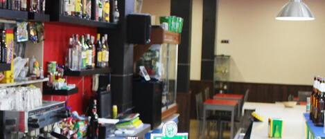 A bar area with shelves of various liquor bottles, a coffee machine, and a 'Tropical' sign.