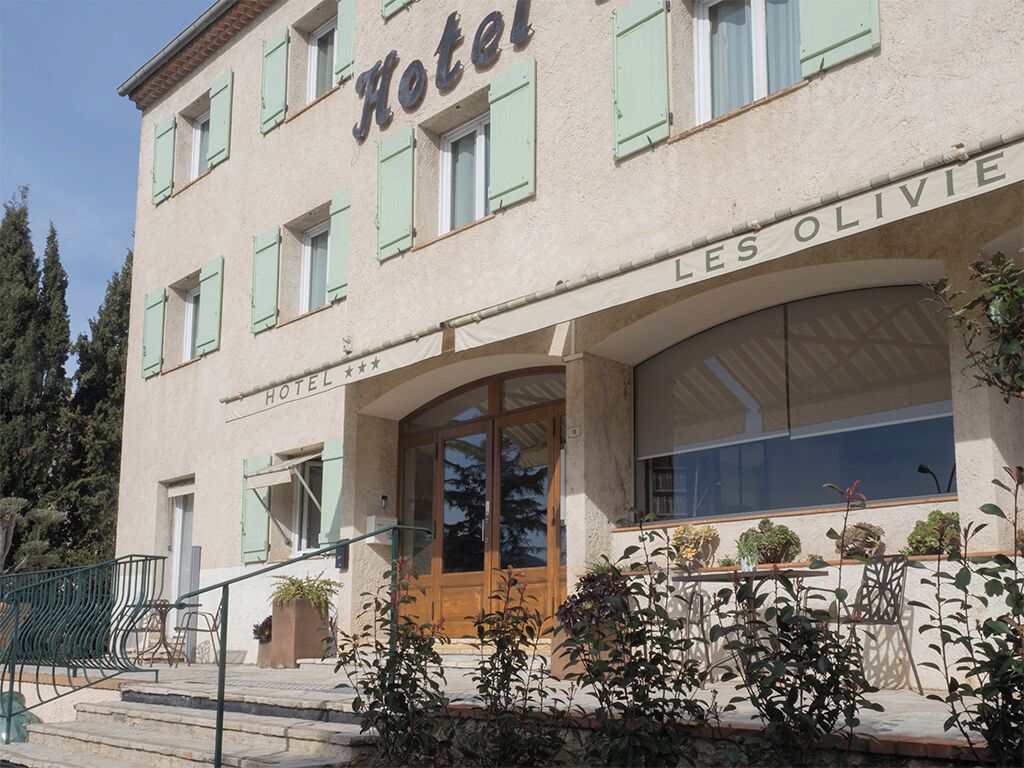 A hotel with a classic facade, a prominent entrance, and a balcony with potted plants.