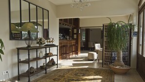A spacious living area with a large rug, a wooden console table, a potted plant, and a bookshelf. - Les Oliviers (Fayence)