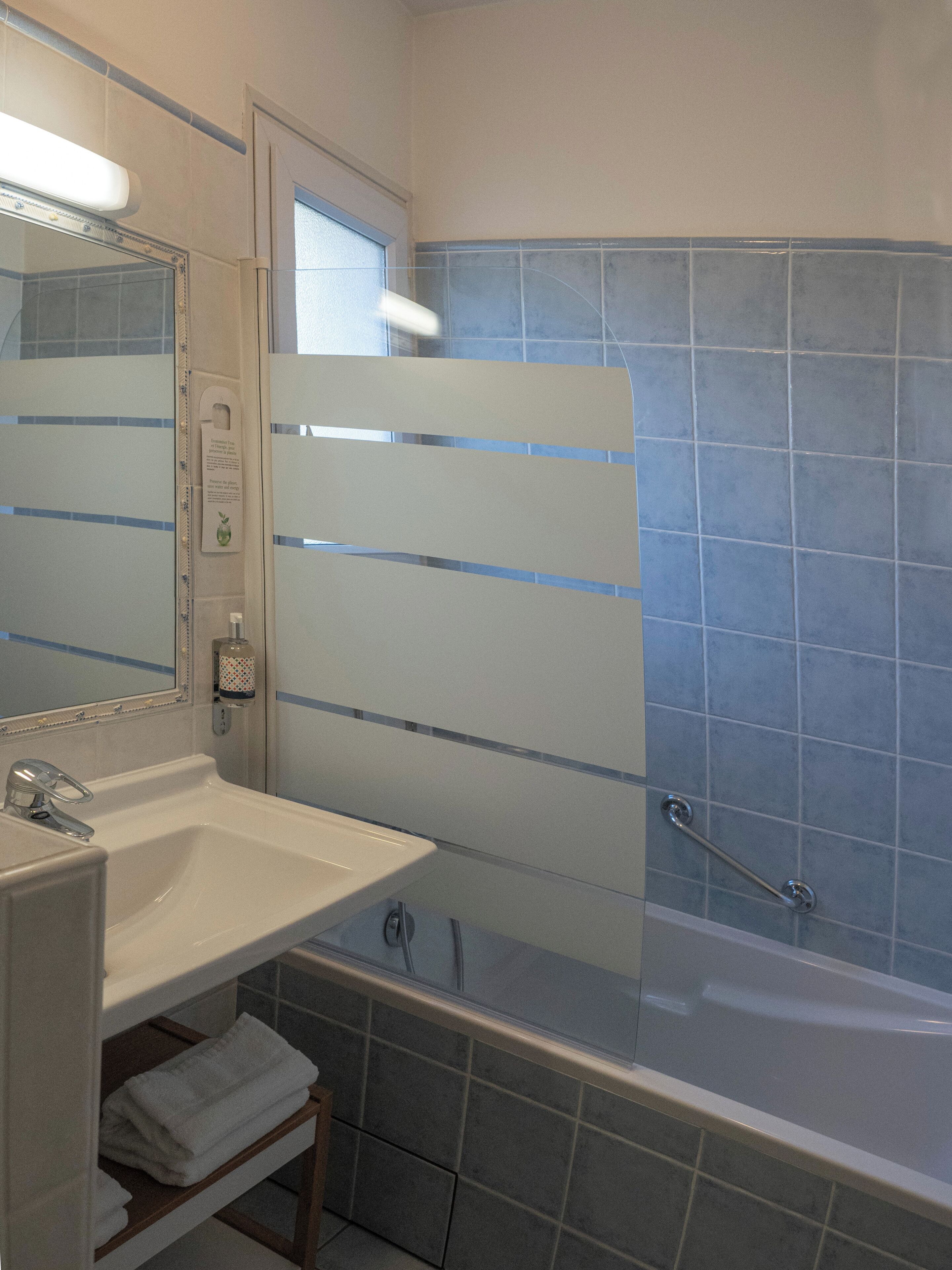A bathroom with a white sink, a mirror, a glass shower enclosure, and a bathtub.