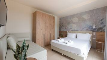 A modern bedroom with a large bed, a sofa, a potted plant, and a wall mural.