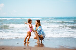 A beach scene with a woman and a child playing near the water. - Canado Family Hotel (Castagneto Carducci)