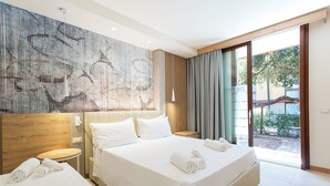 Ein modernes Hotelzimmer mit einem großen Bett, einem kleinen runden Tisch und Blick ins Freie durch eine Schiebetür.
