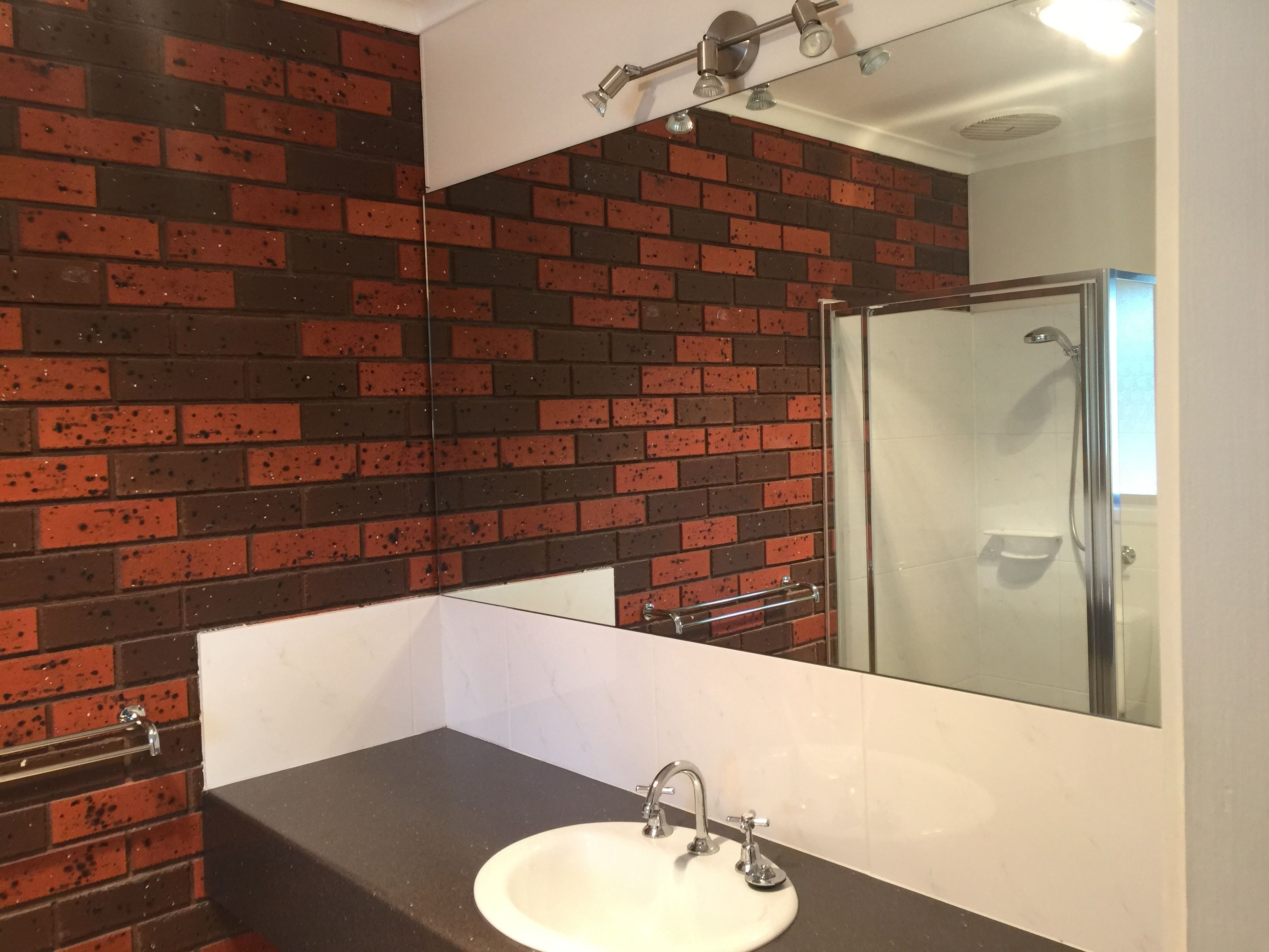 A bathroom with a white sink, a mirror, and a shower.