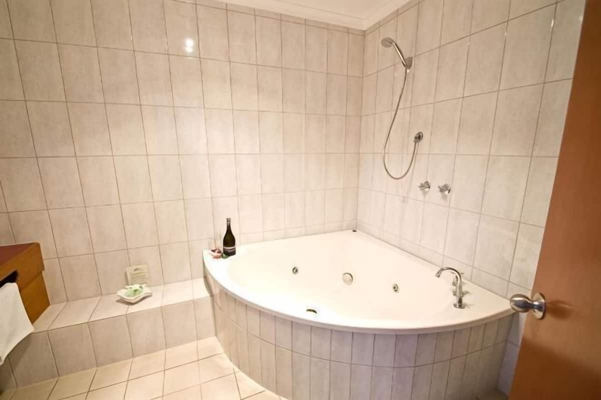 A bathroom with a freestanding bathtub, a showerhead, and a towel rack.
