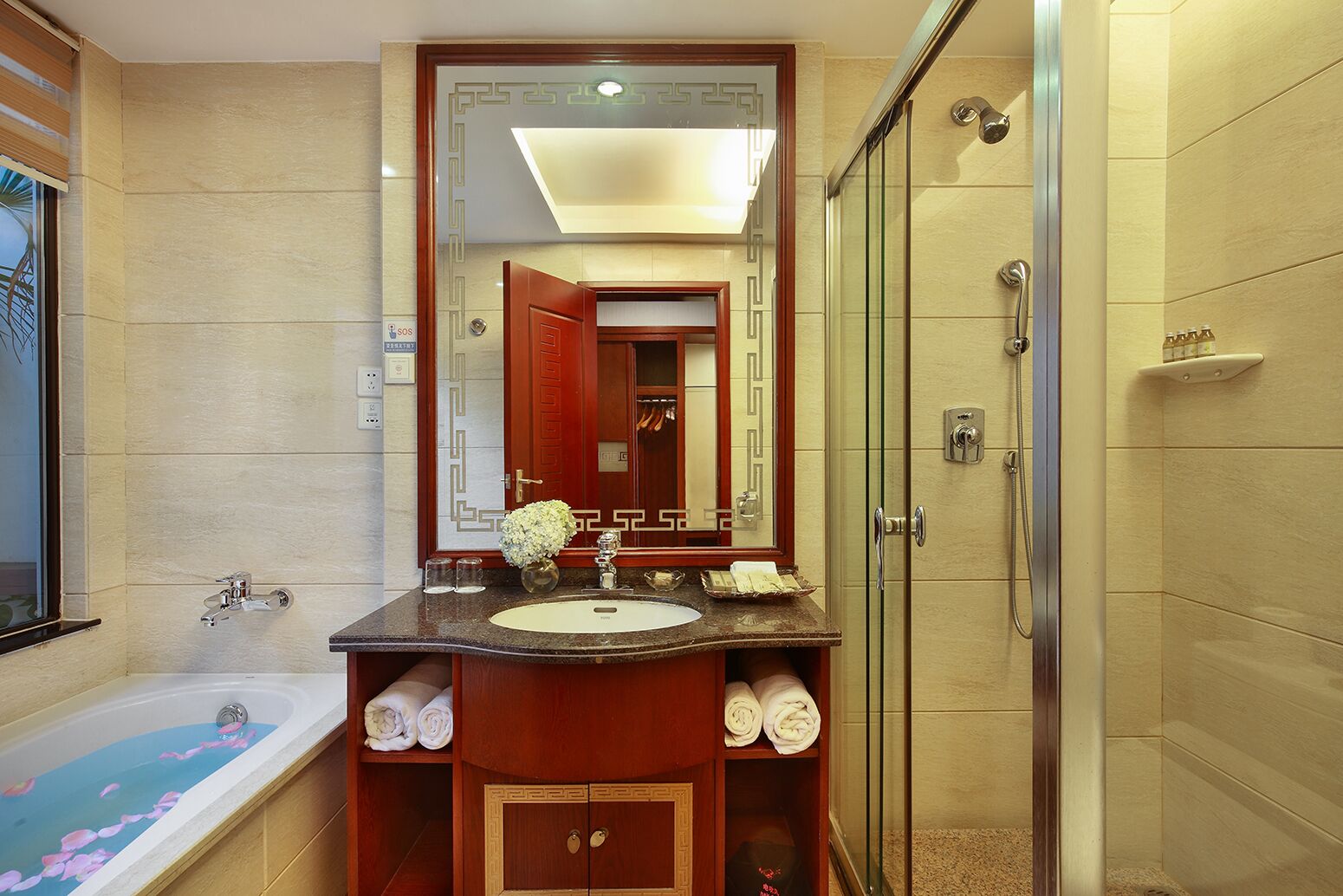 A modern bathroom with a bathtub, a large mirror, a vanity with a sink, and a glass shower enclosure.