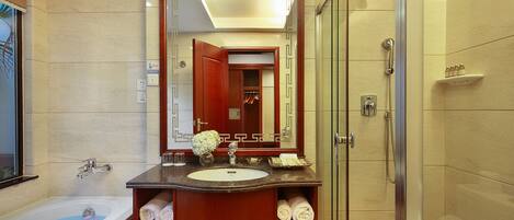 A modern bathroom with a bathtub, a large mirror, a vanity with a sink, and a glass shower enclosure.
