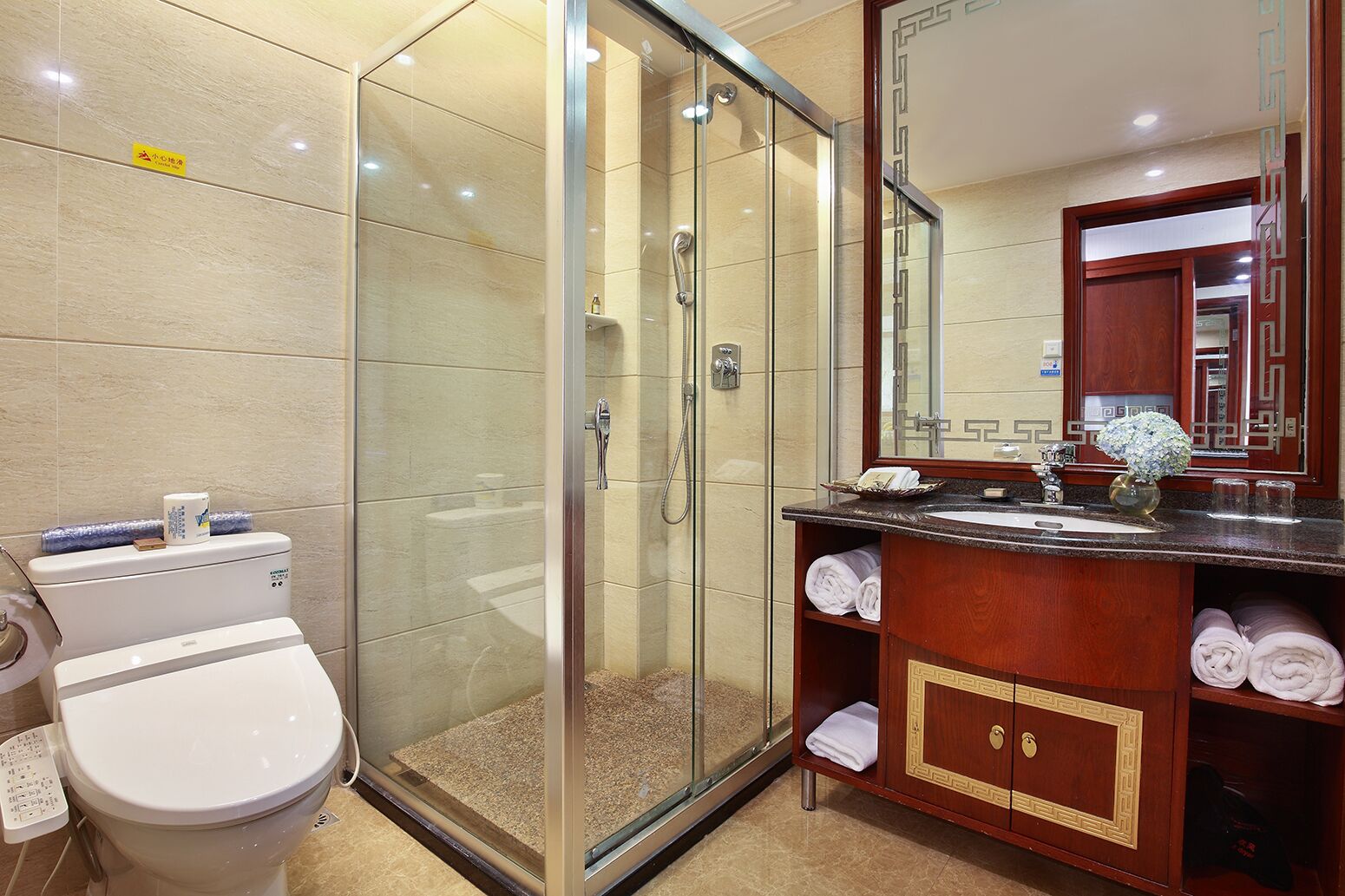 Un baño moderno con ducha de vidrio, inodoro blanco y tocador de madera con espejo.