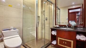 Un baño moderno con ducha de vidrio, inodoro blanco y tocador de madera con espejo.