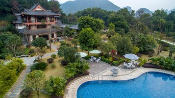 A traditional building with a tiled roof, surrounded by lush greenery and a swimming pool.