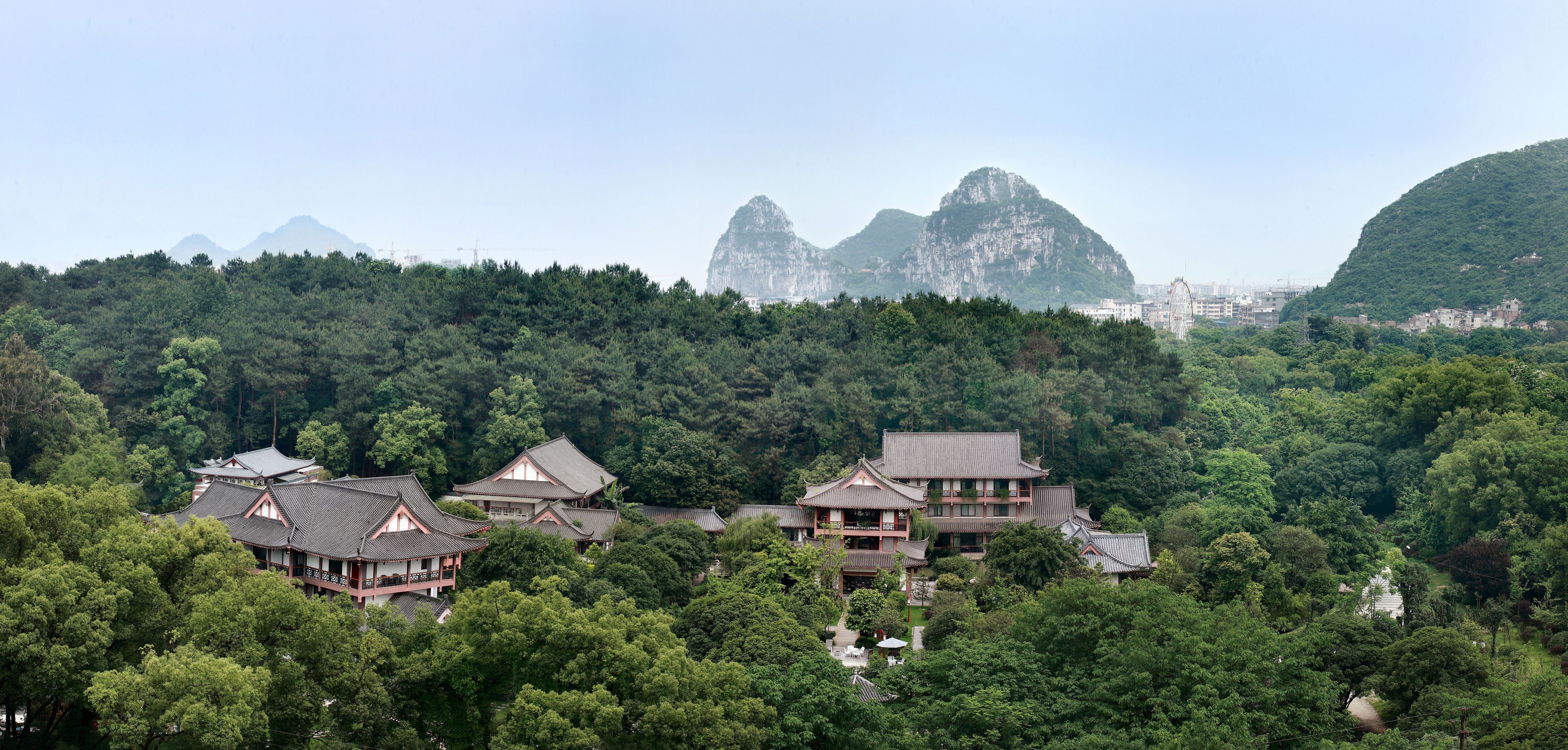 A traditional Japanese-style building complex surrounded by dense forest and mountains.